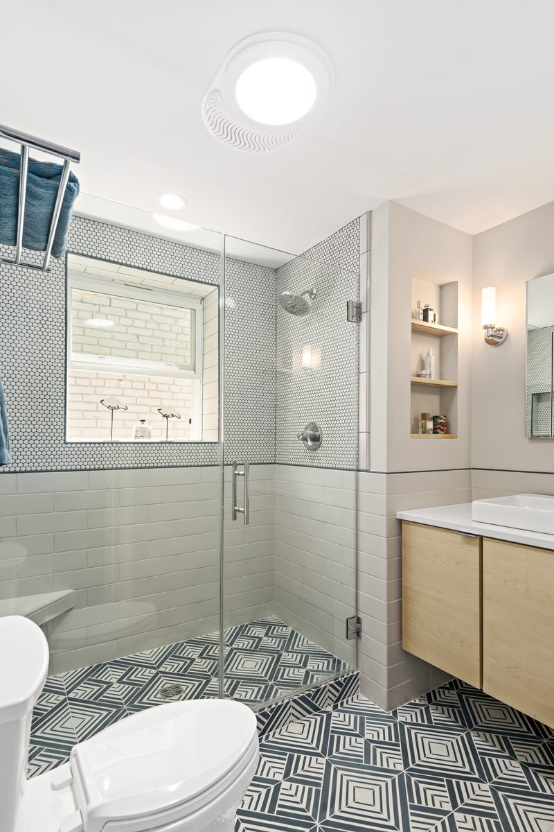 Bath — penny mosaic tile, geometric floor pattern, glass shower with subway tile, light wood vanity