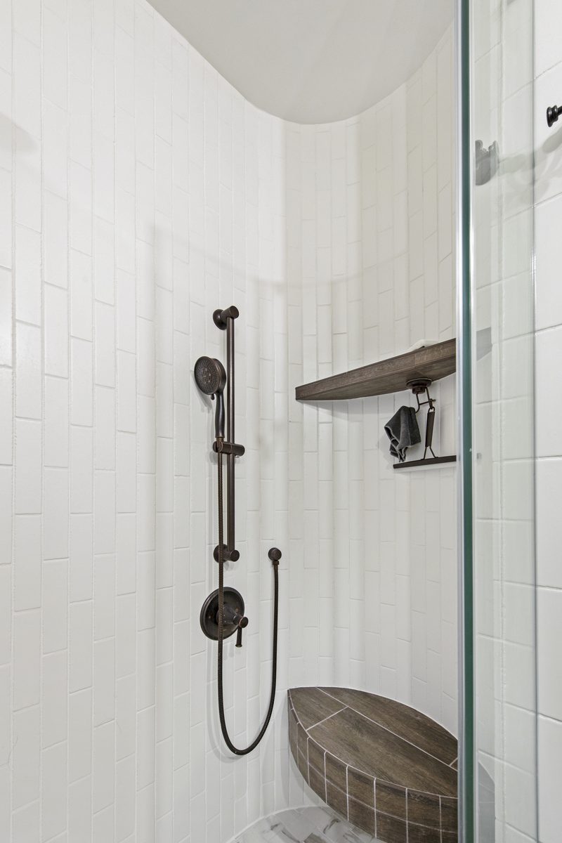 Steam shower — vertical stack tile, oil-rubbed bronze fixtures, built-in wood bench, glass enclosure