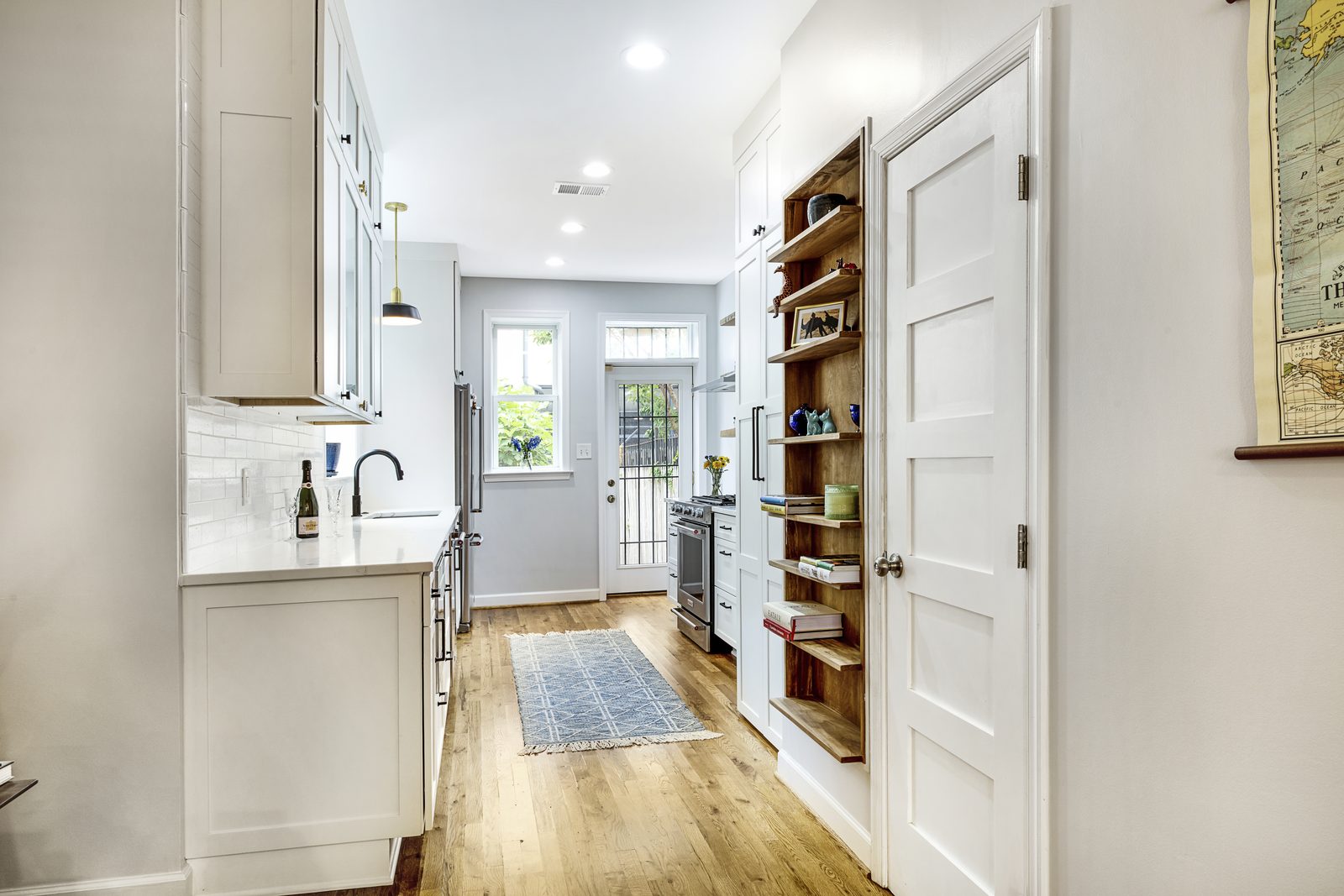 Kitchen with built-in pantry shelves and exposed wood accents leading to rear glass door